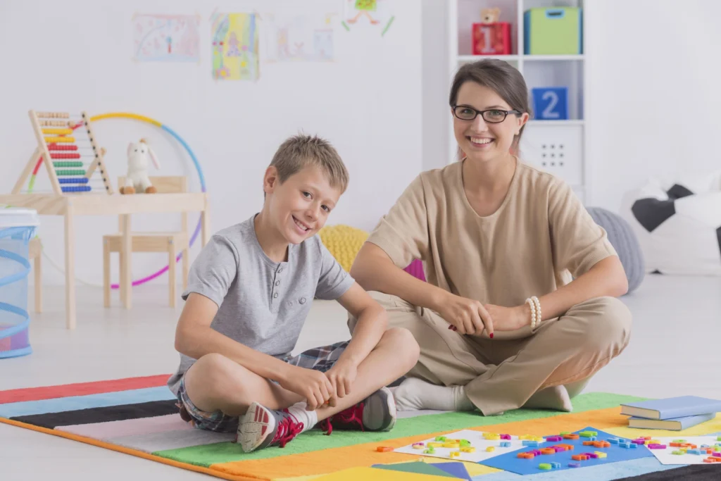 Child and adult sitting on colorful mat.