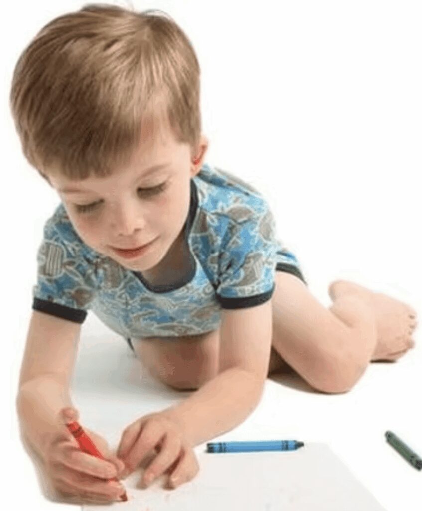 Child drawing with crayons on paper.